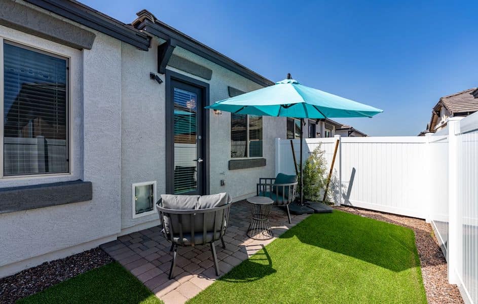 Back yard of one of our townhomes for rent in Queen Creek, AZ, featuring a lawn, umbrella, and outdoor furniture.