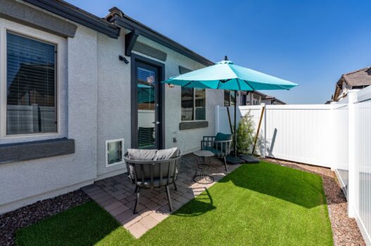 Model backyard at our apartments for rent in Queen Creek, AZ, featuring astroturf, chairs, and an umbrella.