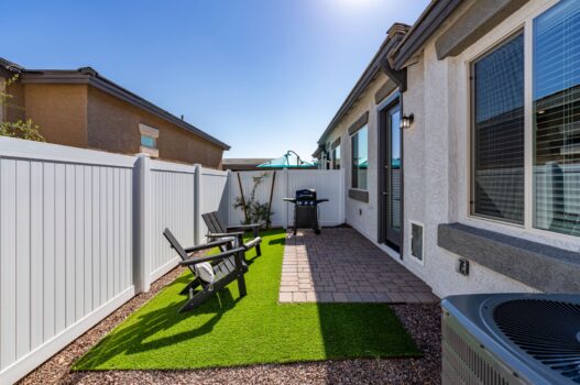 Model backyard at our apartments for rent in Queen Creek, AZ, featuring astroturf, adirondack chairs, and a grill.