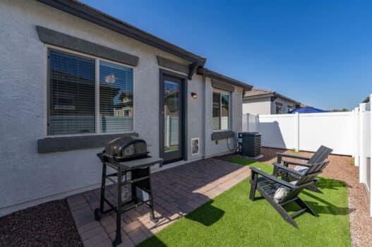 Model backyard at our apartments for rent in Queen Creek, AZ, featuring astroturf, adirondack chairs, and a grill.