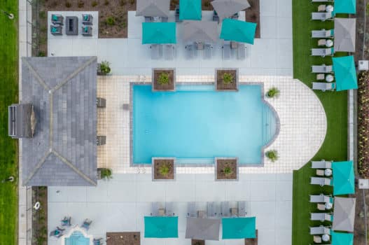 Aerial photograph of the pool area at our apartments in Queen Creek, featuring umbrellas, tables, and beach chairs.