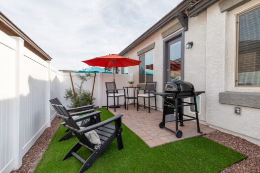 Model back yard at our apartments in Queen Creek, featuring astroturf, a grill, and glass doors to the apartment.