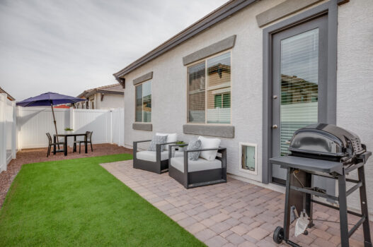 Model back yard at our apartments in Queen Creek, featuring astroturf, a grill, and glass doors to the apartment.